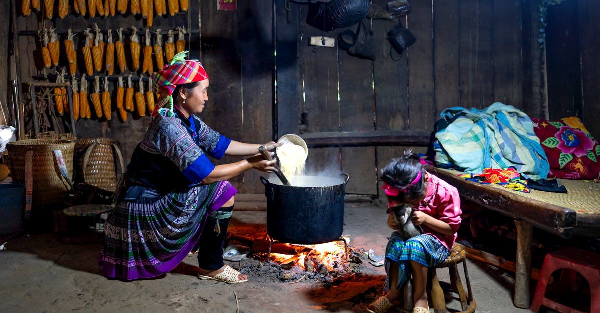 Play Pokémon Go On An Amazon Fire Phone? - Content ethnic mom in traditional wear pouring rice into cauldron above fire against anonymous girl playing with cat at home