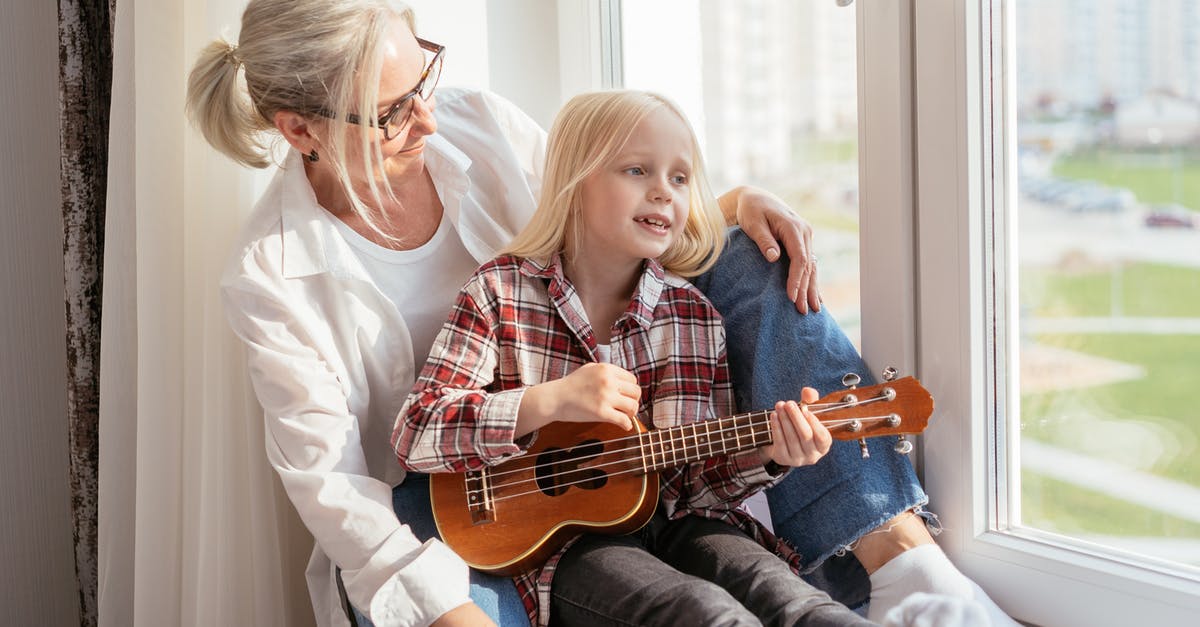Playing Age of Mythology on Windows 10 - A Little Girl Playing an Ukulele while Sitting by a Window with her Grandmother Playing Age of Mythology on Windows 10 - A Little Girl Playing an Ukulele while Sitting by a Window with her Grandmother