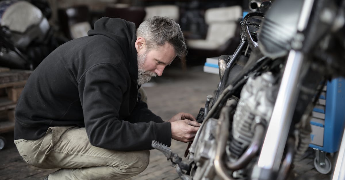 Playstation 4 Broken HDMI Port Repair. How to fix this PS4? - Side view of focused male mechanic in casual wear sitting near motorbike and examining details details in workshop Playstation 4 Broken HDMI Port Repair. How to fix this PS4? - Side view of focused male mechanic in casual wear sitting near motorbike and examining details details in workshop