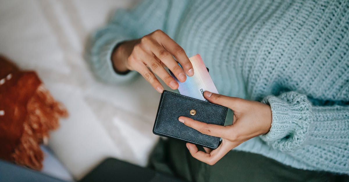 Playstation Now - Is there any way to use my PSN wallet only, instead of having to add a credit card info? - From above crop anonymous female in casual sweater taking credit card from wallet and lying on bed with laptop before making online purchase