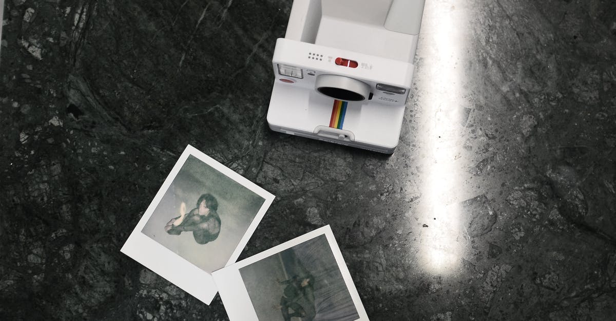 Playstation Plus Instant Game Collection on same device, from multiple countries - Modern instant photo camera and photos placed on marble surface