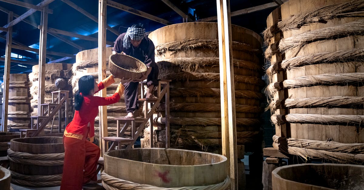 Playstation store Destiny help [duplicate] - Woman helping male colleague standing on ladder while working in fish sauce factory together