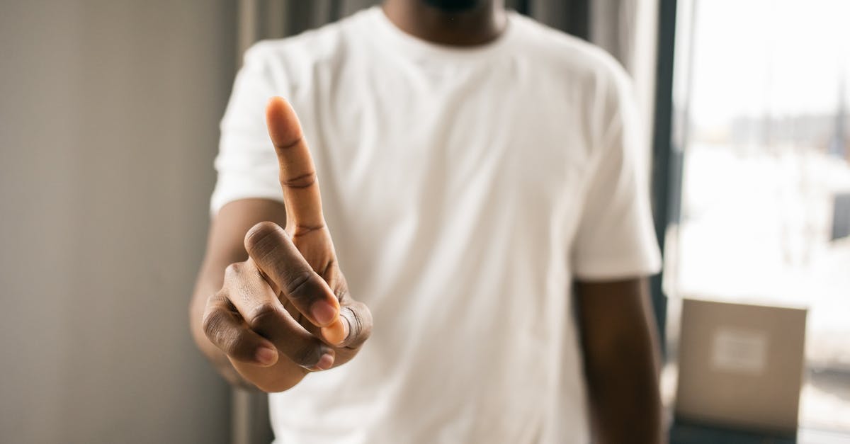 Pointers to closest portals don't show up - Crop anonymous African American male in white t shirt showing stop gesture with index finger pointing up in light room on blurred background Pointers to closest portals don't show up - Crop anonymous African American male in white t shirt showing stop gesture with index finger pointing up in light room on blurred background