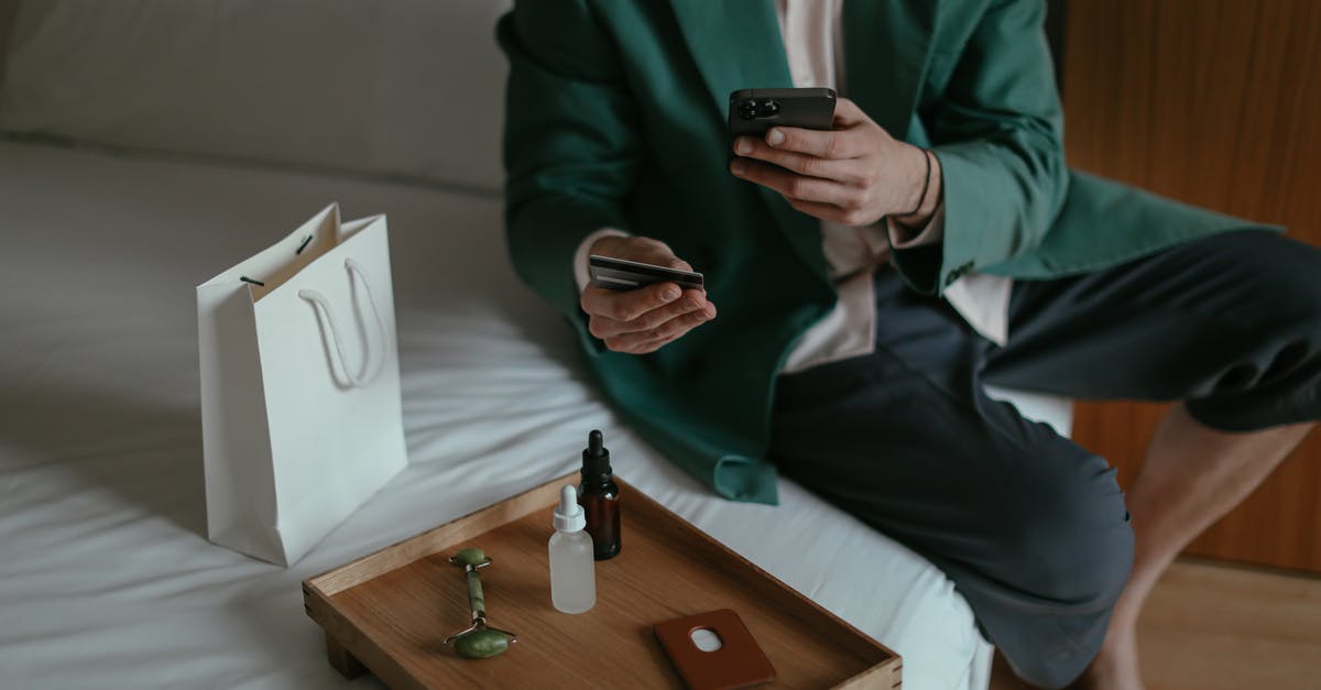 Pokémon bank and home - Anonymous man using smartphone while placing order with credit card sitting near cosmetic products Pokémon bank and home - Anonymous man using smartphone while placing order with credit card sitting near cosmetic products