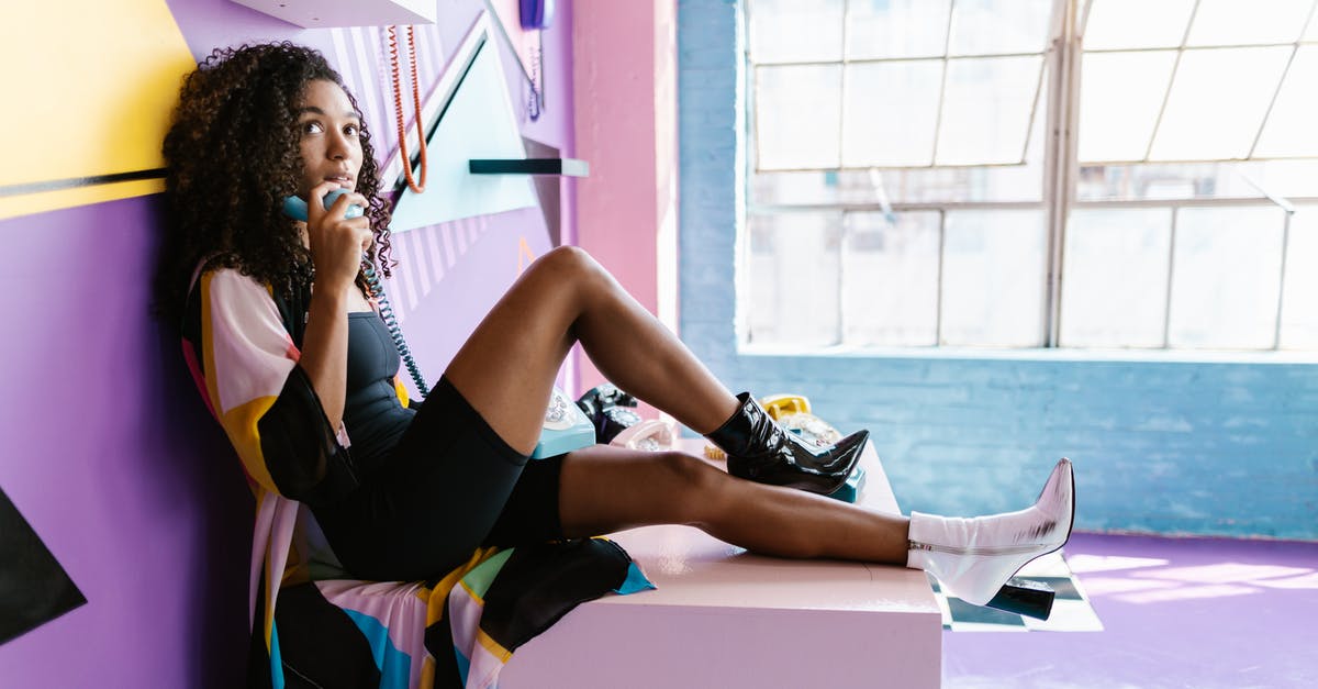 Pokémon on Windows Phone - Woman Holding a Vintage Phone and Sitting in Front of a Colorful Wall with Vintage Phones