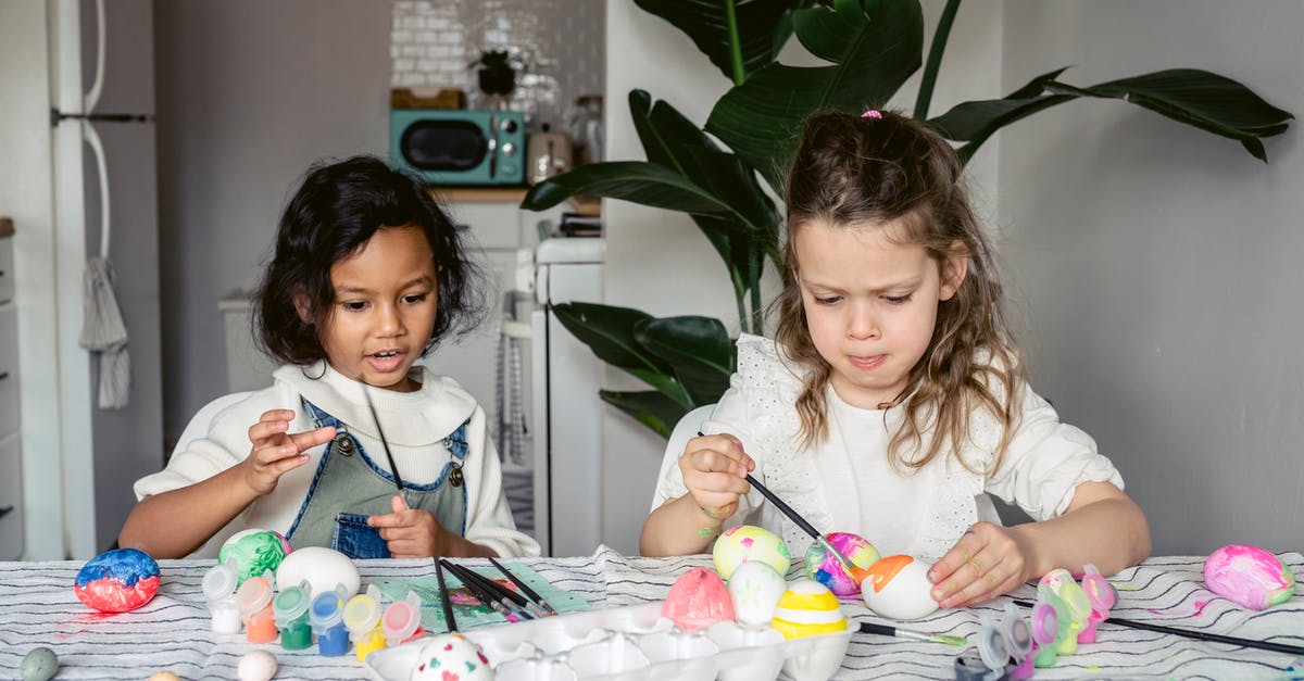Pokemon go egg progress color changes - Concentrated multiracial girls painting white eggs with paintbrushes while sitting at table with paints in kitchen during Easter holiday at home