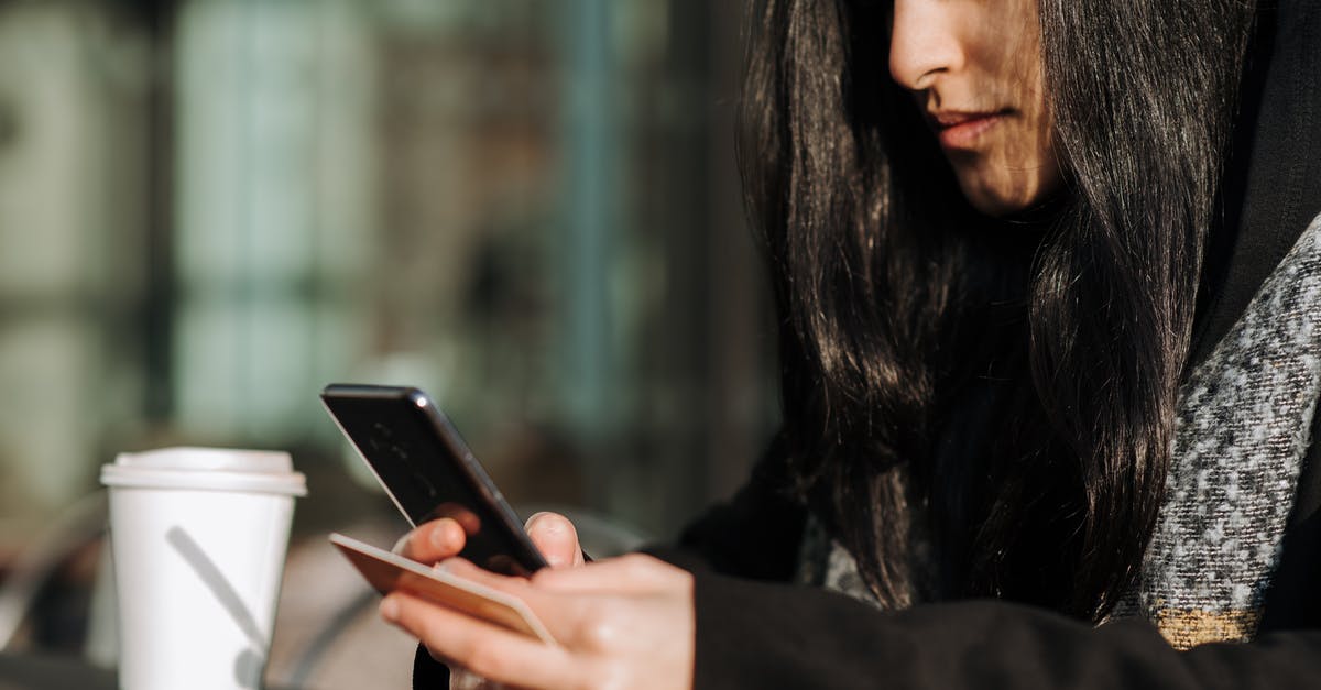 Policy card effectiveness timing - Crop ethnic shopper making purchase on smartphone with debit card