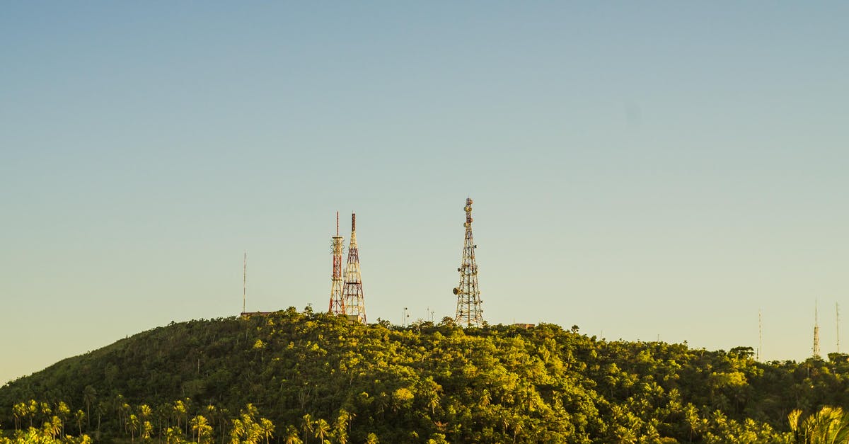 Polish tech tree, radio R-123 - Metal tall telecommunication towers on high hills covered with tropical trees with fresh verdant foliage under cloudless sky Polish tech tree, radio R-123 - Metal tall telecommunication towers on high hills covered with tropical trees with fresh verdant foliage under cloudless sky