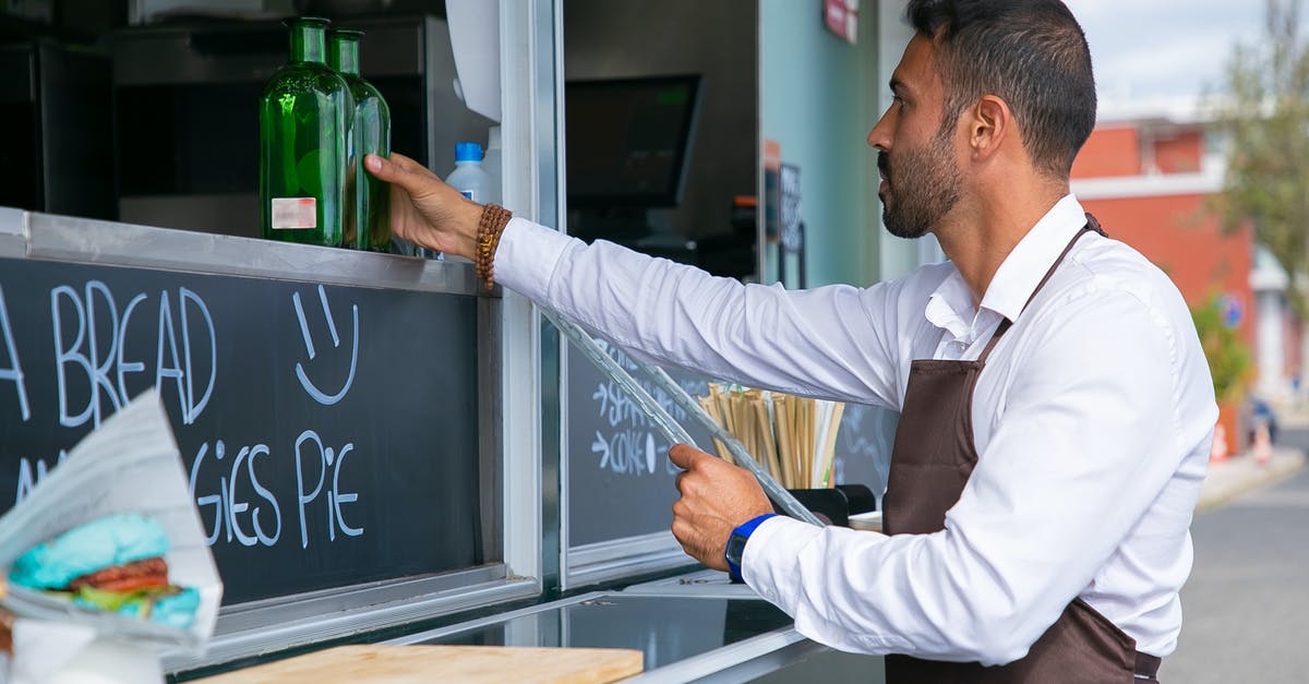 Prepared food barrels don't have a category in the trade depot - Focused ethnic male worker placing glass bottle at counter Prepared food barrels don't have a category in the trade depot - Focused ethnic male worker placing glass bottle at counter