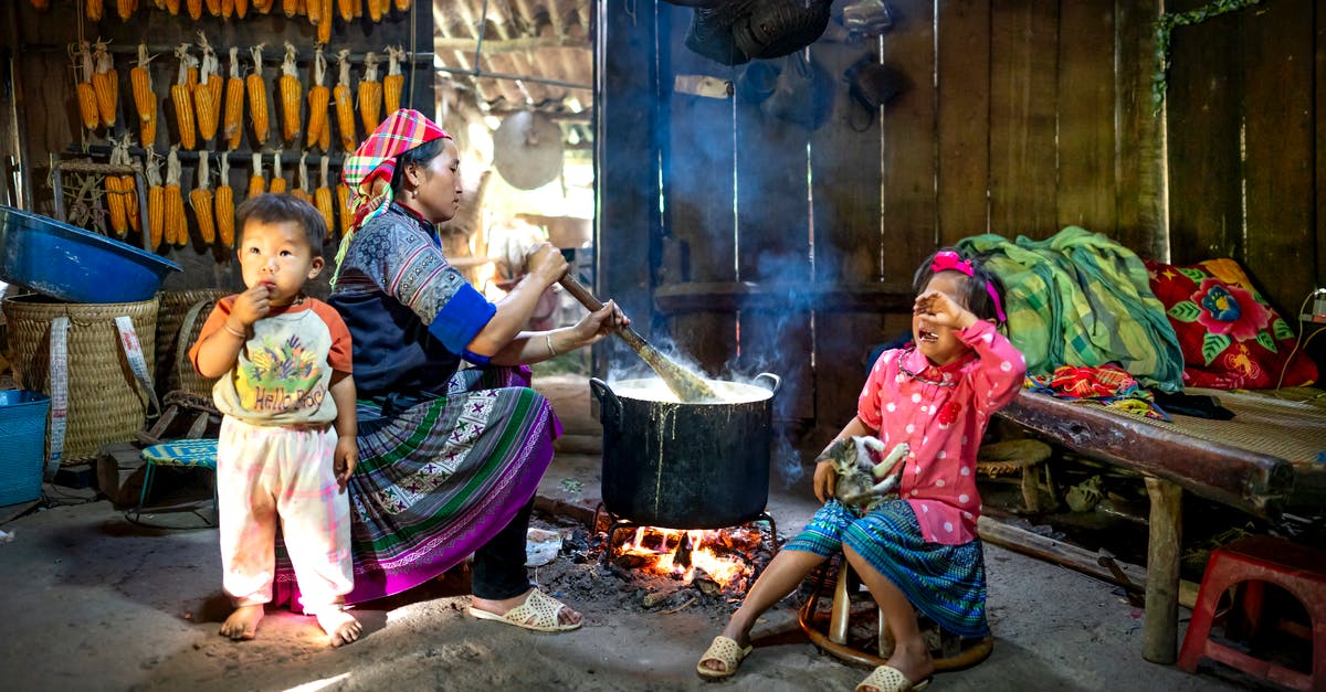 Prepared food barrels don't have a category in the trade depot - Side view of Asian woman in colorful outfit sitting with children and preparing food on bonfire in wooden rural barn in daytime Prepared food barrels don't have a category in the trade depot - Side view of Asian woman in colorful outfit sitting with children and preparing food on bonfire in wooden rural barn in daytime