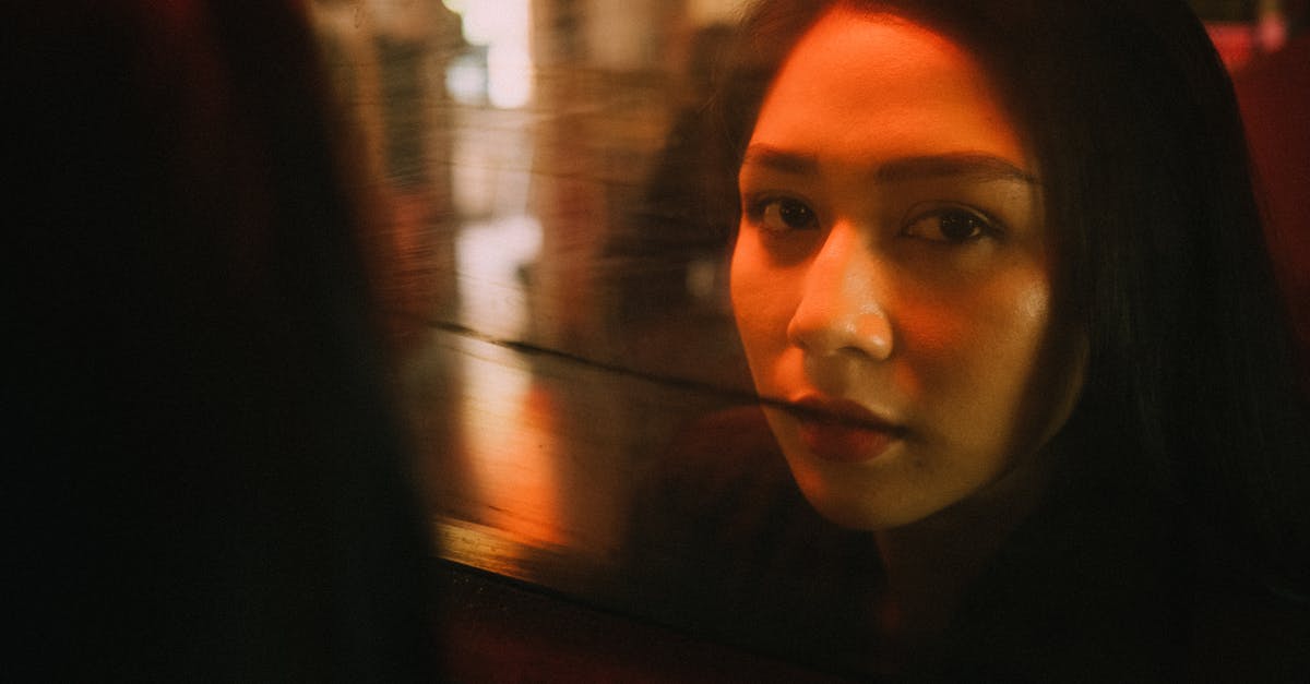 Presents effects during free time - Content ethnic female reflecting in glass window and looking at camera in cozy cafe