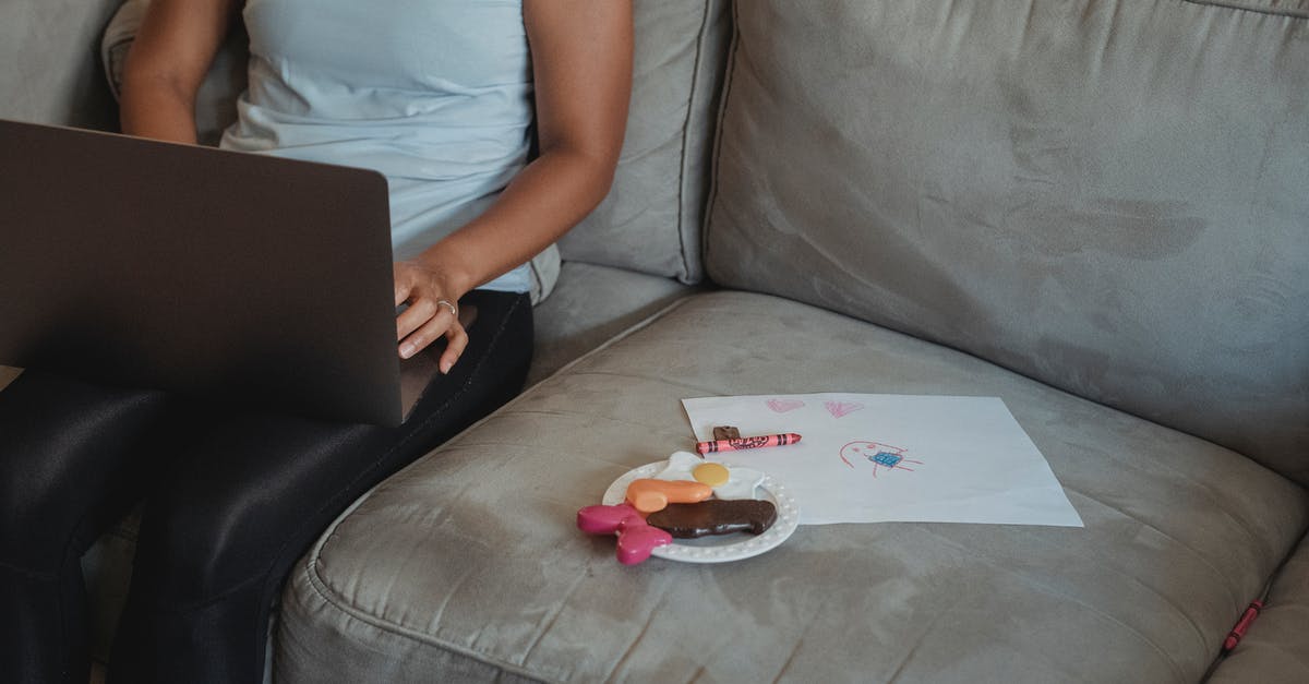 Pressure Plates and Chat [duplicate] - Crop anonymous female in casual wear sitting on comfortable sofa with toy sweets and drawing and browsing internet on laptop