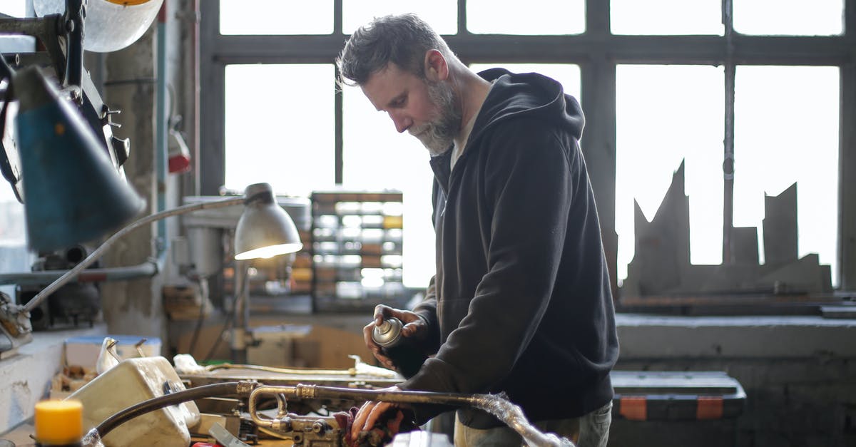 Prevent griefing - Serious bearded mechanic working at workbench in light workshop