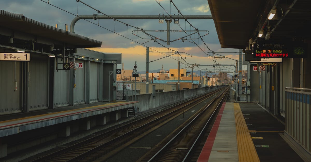 Preventing Iron golems from spawning outside the spawner platform? - Railroad station with metal rails and glowing signboards on street in city with cables and buildings in distance on evening time