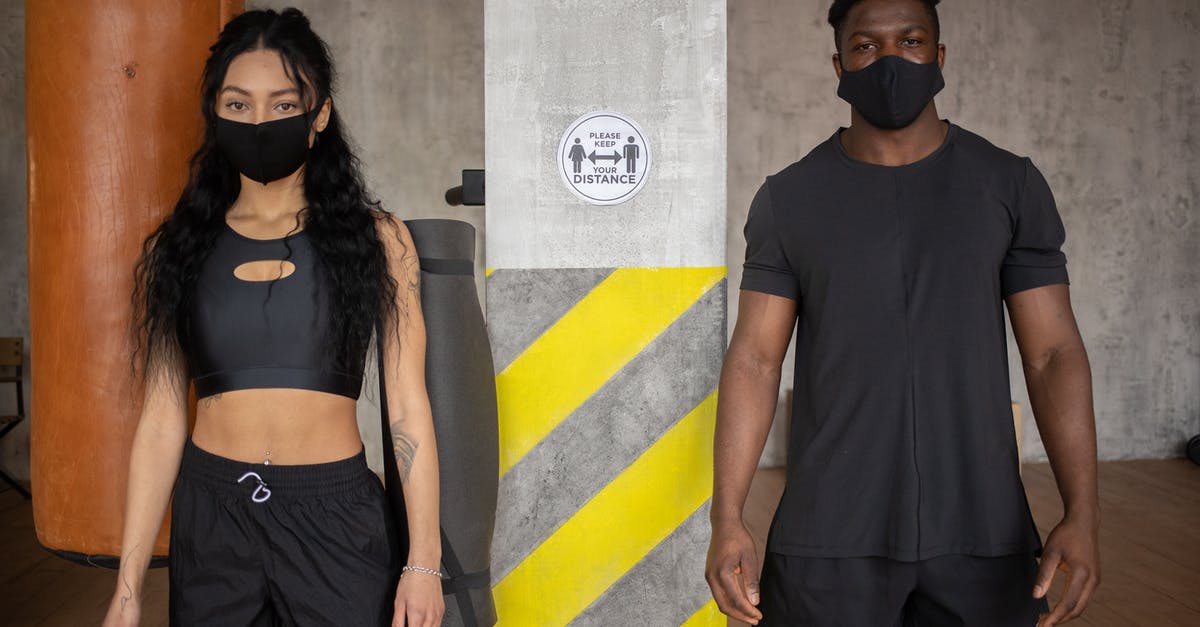 Preventing the spread of infection - Young diverse female and African American male in protective masks standing at distance and looking at camera