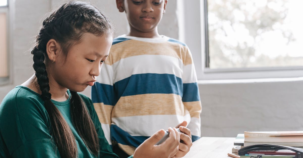Primary ps4 and game sharing [duplicate] - Funny little Asian girl playing game on smartphone while spending break with black classmate at school
