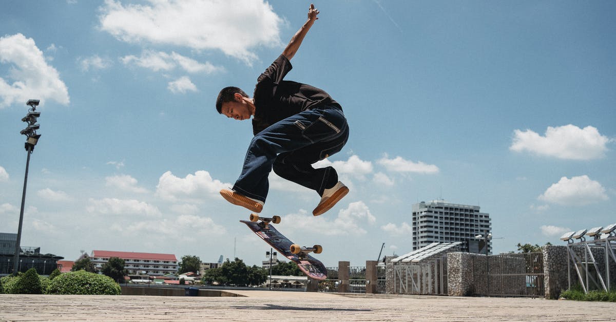 Prince of Persia Level 3 - Making the jump - Ethnic man jumping with skateboard on sidewalk Prince of Persia Level 3 - Making the jump - Ethnic man jumping with skateboard on sidewalk