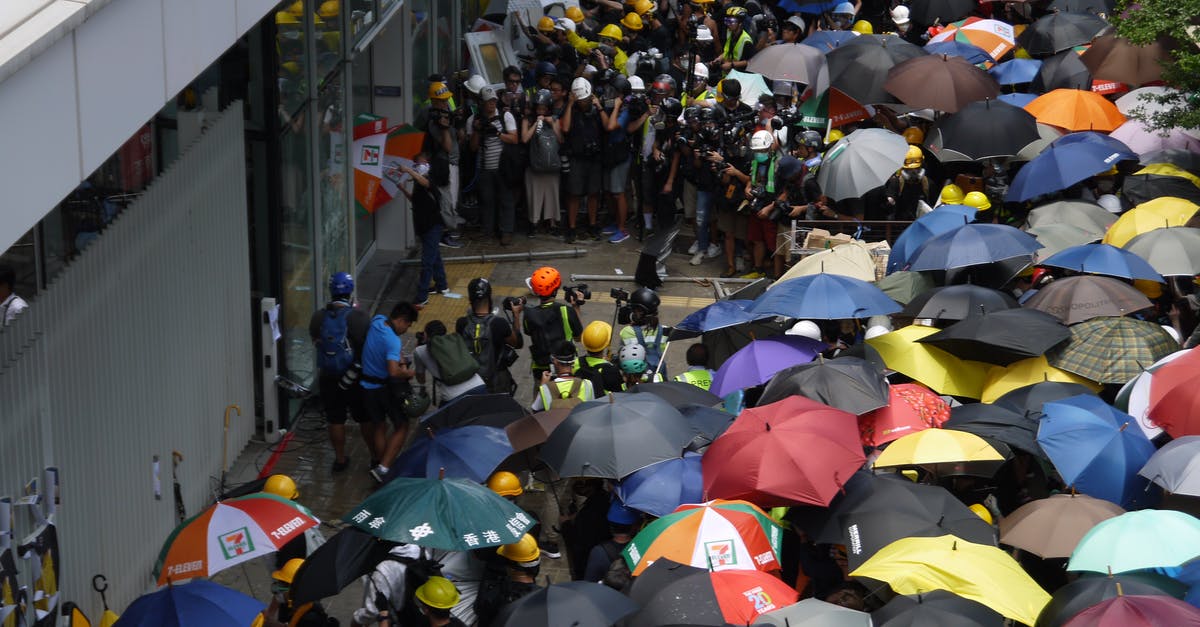 Problem in moving Clash Royale account from android to iOS - Crowded square with group of protestants near facade of building in rainy weather waiting in front of entrance