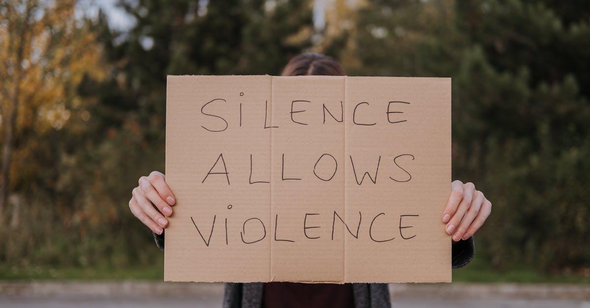 Problem with activating Spore (four options with languages that are not English) - Anonymous person showing slogan silence allows violence on cardboard on road near green trees Problem with activating Spore (four options with languages that are not English) - Anonymous person showing slogan silence allows violence on cardboard on road near green trees