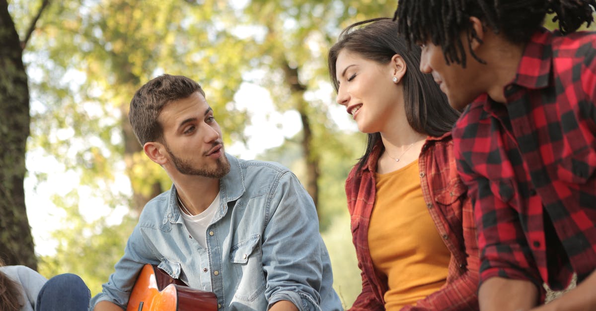 Problems with share play - Denim dressed man playing guitar and singing while sitting with friends in park