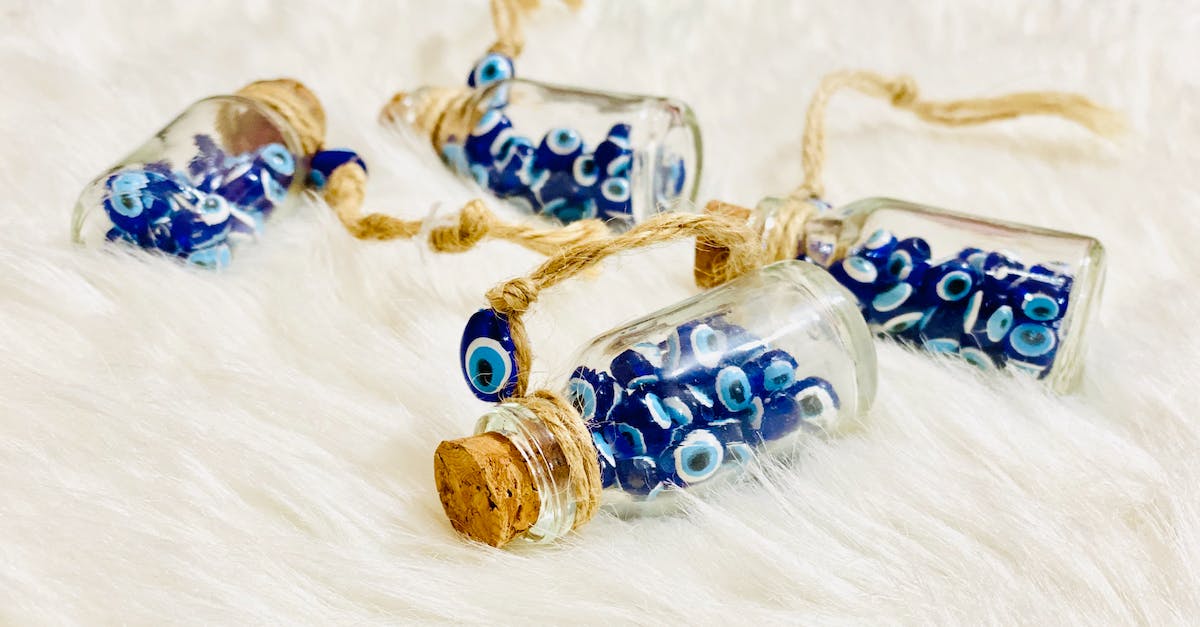 Protection from Evil Rain? - From above of identical small decorative bottles with blue evil eyes and round bungs with threads on soft plaid Protection from Evil Rain? - From above of identical small decorative bottles with blue evil eyes and round bungs with threads on soft plaid