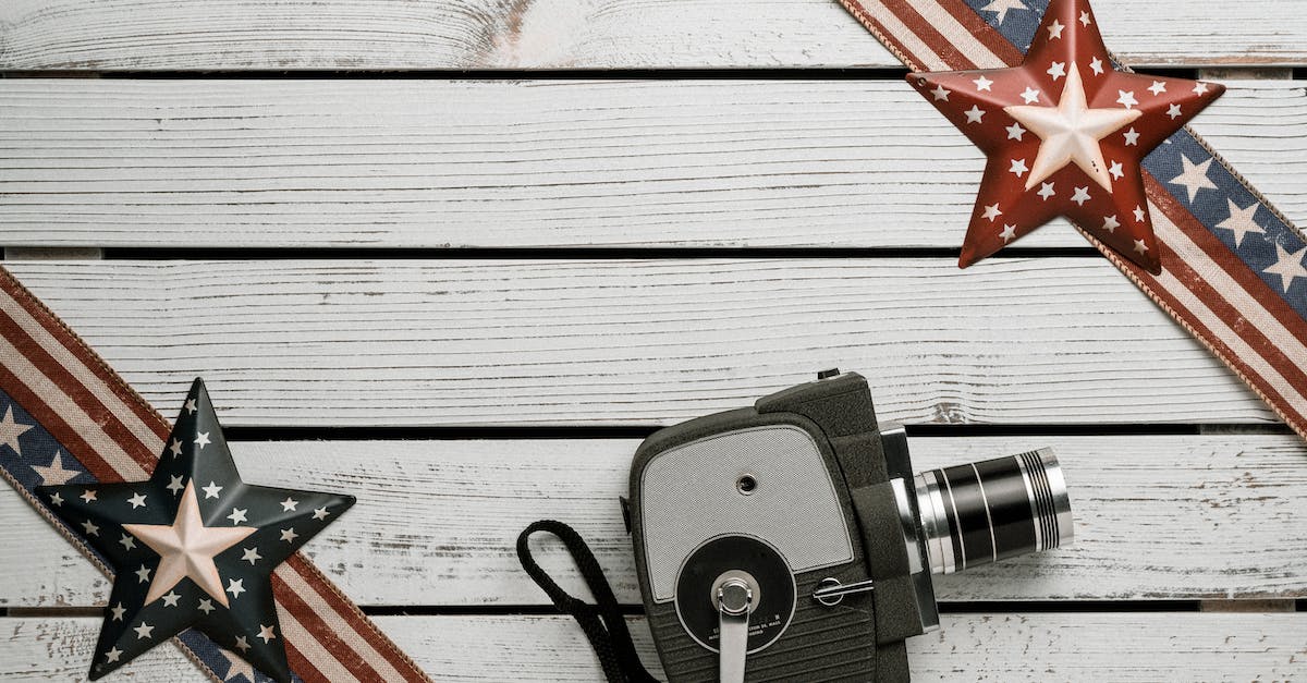 PS3 copy video files from BD-R to HDD - Top view arrangement of vintage video camera placed on white plank surface between decorative USA national flag ribbons