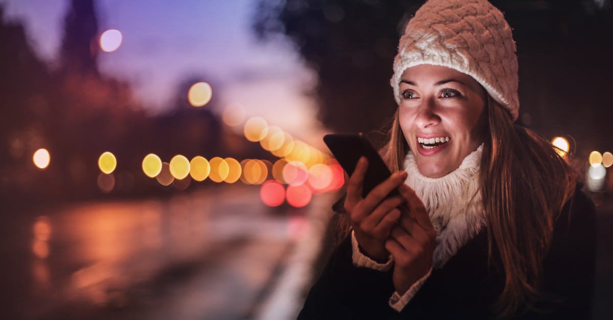 PS4 LAN party Online - Cheerful woman recording voice message on smartphone in street