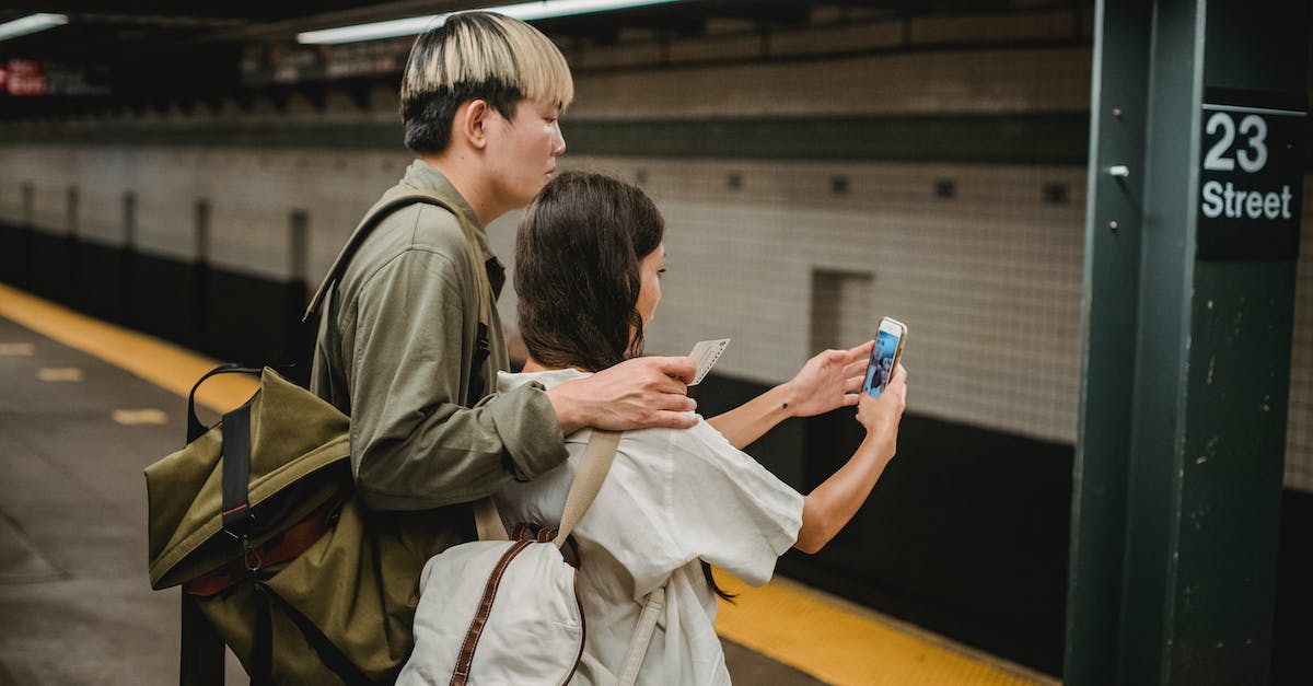 Railroad Tycoon II screen resolution - Side view of ethnic young female in casual clothes and backpack taking selfie with Asian boyfriend on smartphone while standing on platform in subway station