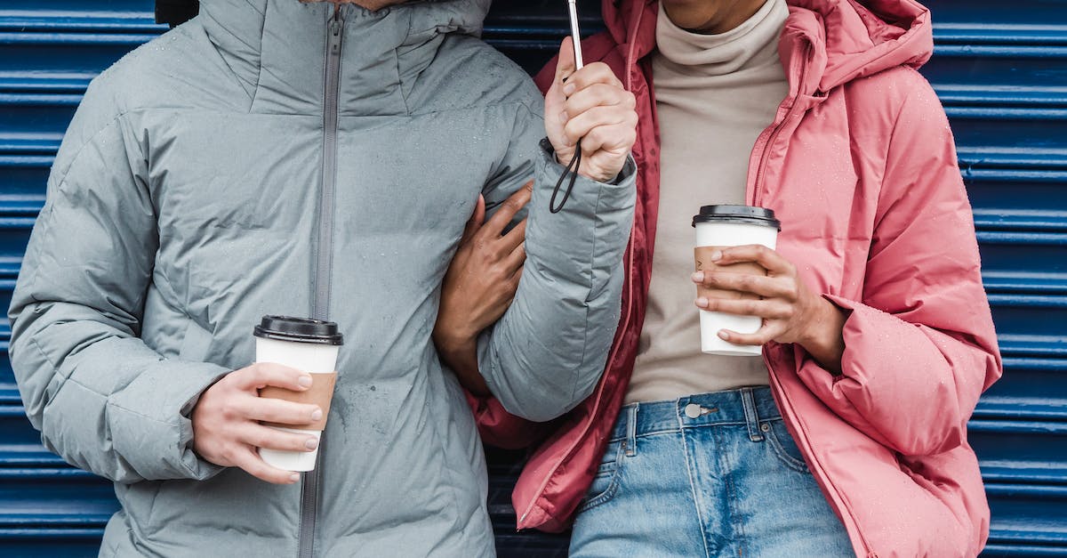 Rain arrows in random positions within bounds? [duplicate] - Crop smiling multiethnic couple wearing warm outerwear standing together with coffee cups in rainy day