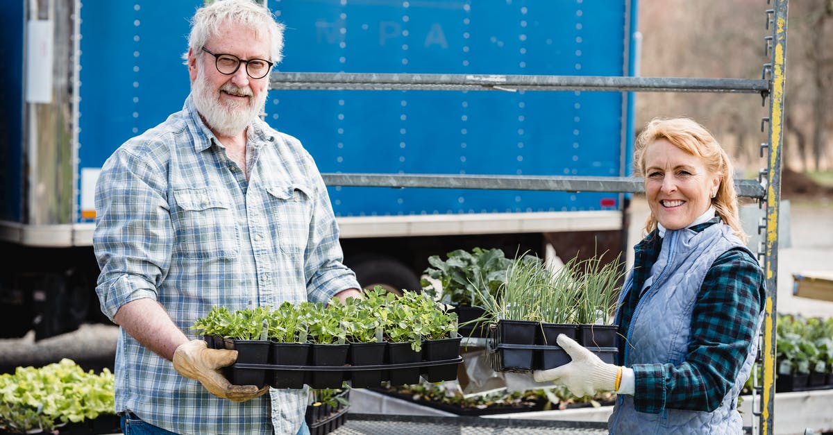 Raising a dweller's happiness - Elderly Couple Holding Potted Plants while Smiling