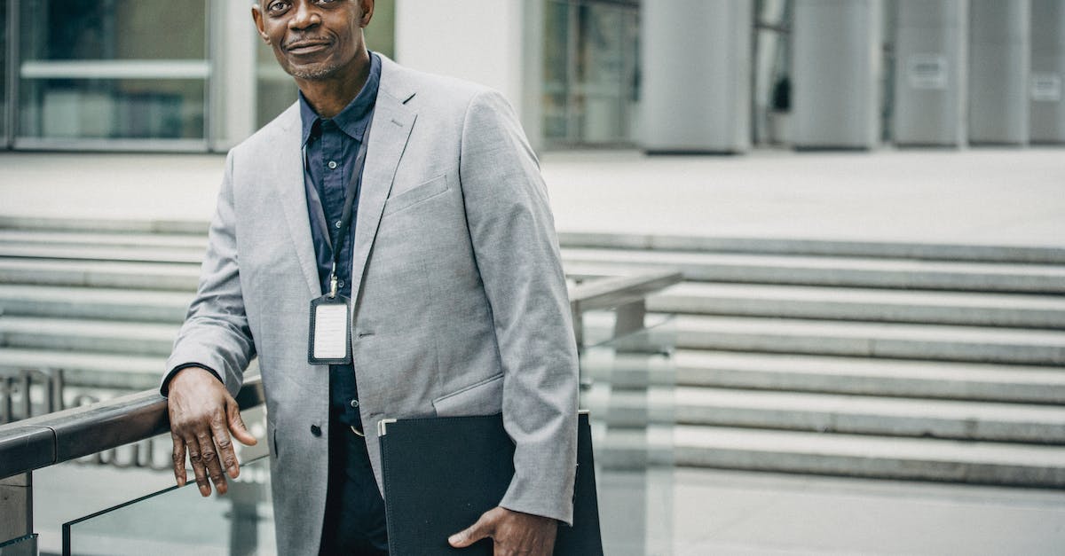 R&D center is closed in career - Positive black businessman leaning on railing near modern business center
