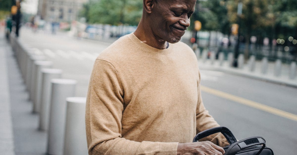 R&D center is closed in career - Frowning black businessman with personal case looking inside and grimacing while standing in street R&D center is closed in career - Frowning black businessman with personal case looking inside and grimacing while standing in street