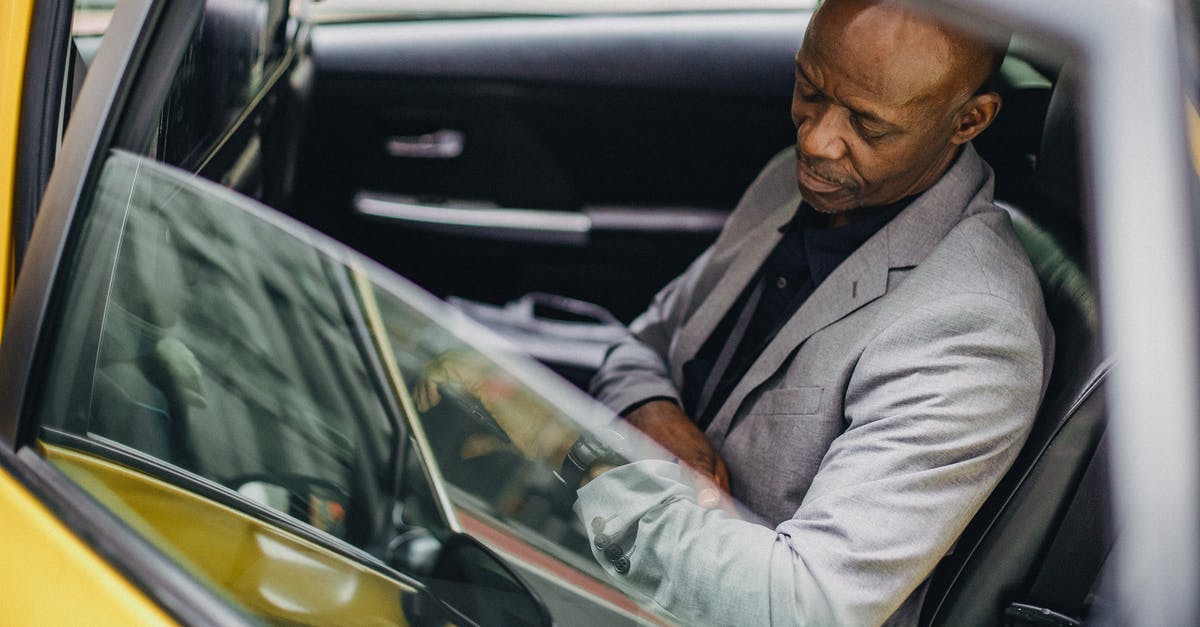Redstone repeater delay if activated - Side view punctual adult African American businessman in formal clothing sitting in taxi car and checking time on wristwatch