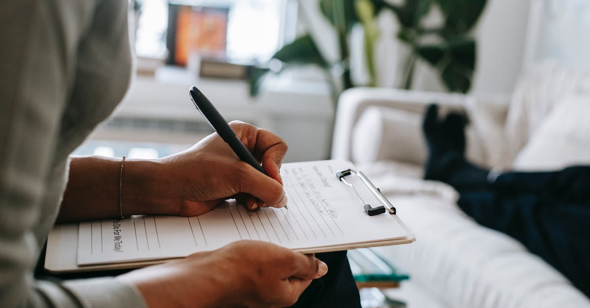 Redstone trouble - Unrecognizable ethnic female therapist taking notes on clipboard while filling out form during psychological appointment with anonymous client lying on blurred background