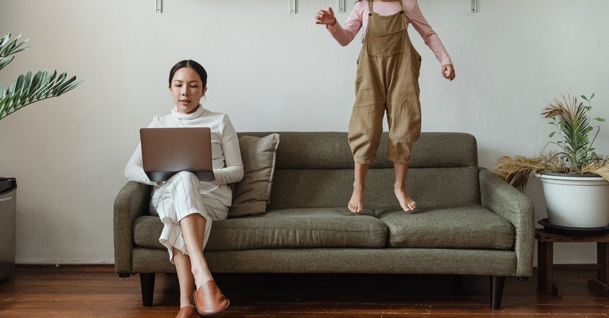 Remote play on PS5 - Focused mother working on laptop near disturbing daughter