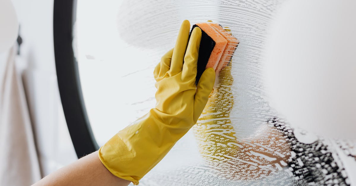 Remove donated troops during preparation phase - Anonymous person in yellow rubber gloves using simple sponge for cleaning mirror in bathroom