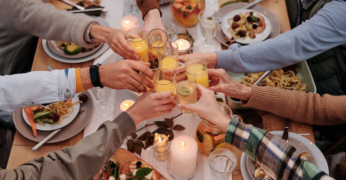 Remove From Family Share - From above of crop friends enjoying dinner with candles while cheering with glasses of drinks