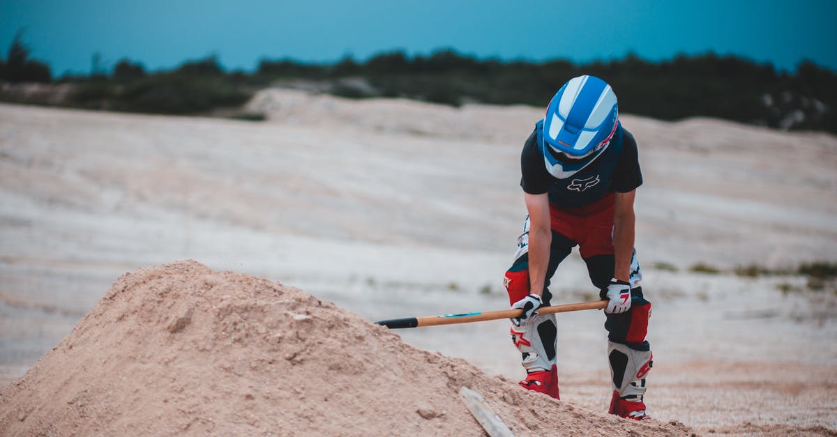 Remove too much sand from The End - Unrecognizable man with shovel near sand