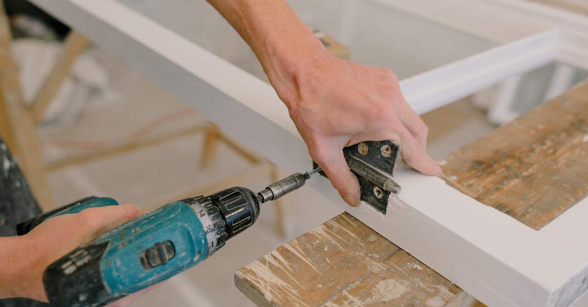 Replace the item crafted with a tag [duplicate] - Unrecognizable professional male master using cordless screwdriver to install metal hinge on wooden window in light room during repair works