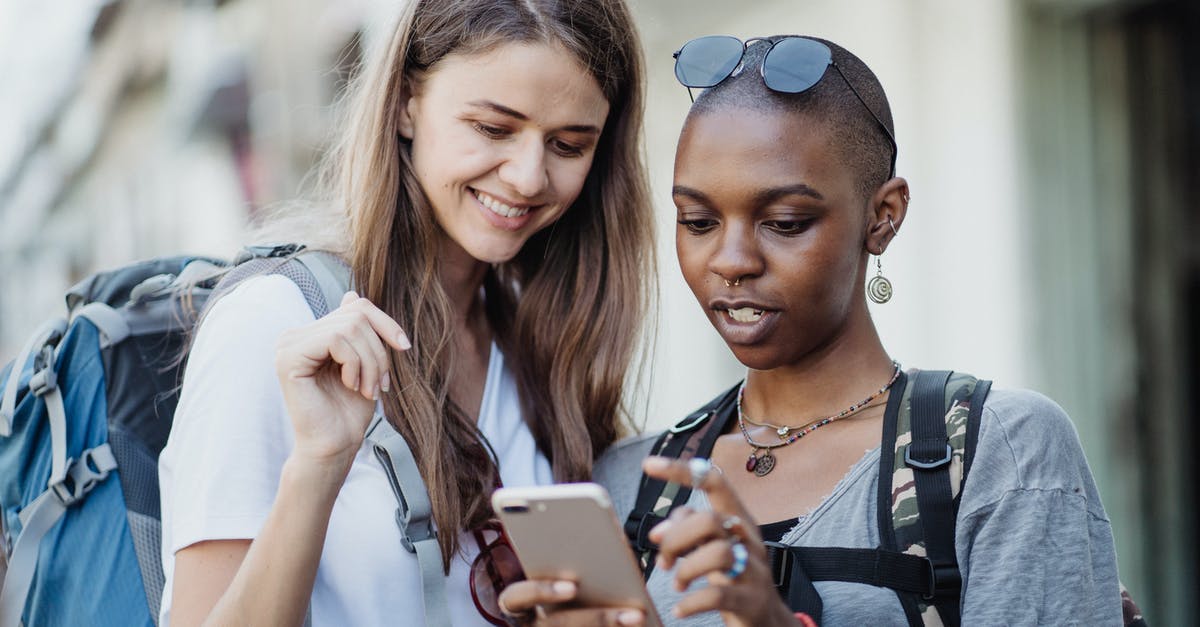 Rewarded more for visiting Pokestops I've never visited before? - Women Travelers Visiting City with Backpacks Using Smart Phone