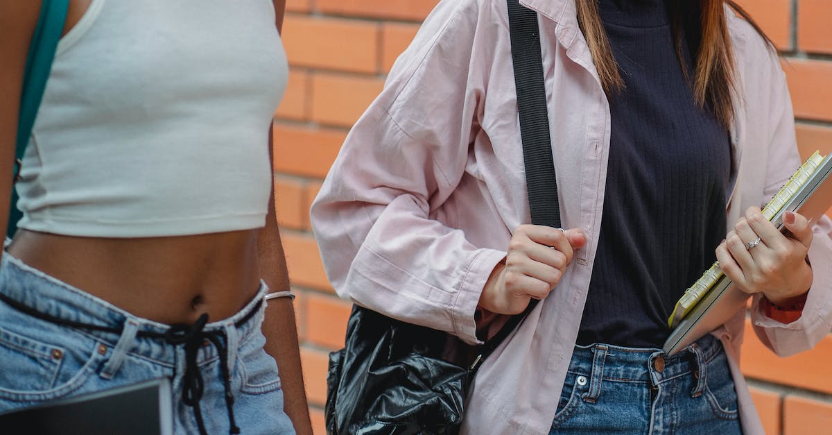 Right time to build school - Crop anonymous black lady with backpack and female friend with netbook walking near university building during break Right time to build school - Crop anonymous black lady with backpack and female friend with netbook walking near university building during break