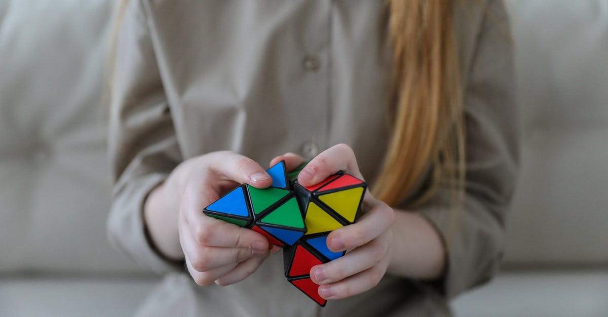 Same game doubly shared on Steam - Crop anonymous girl demonstrating and solving colorful puzzle with triangles in soft focus