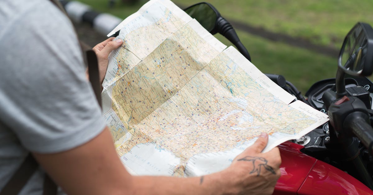 Searching for specific metadata in maps - Side view of crop unrecognizable male in casual clothes with backpack sitting on motorcycle while studying city map on street Searching for specific metadata in maps - Side view of crop unrecognizable male in casual clothes with backpack sitting on motorcycle while studying city map on street