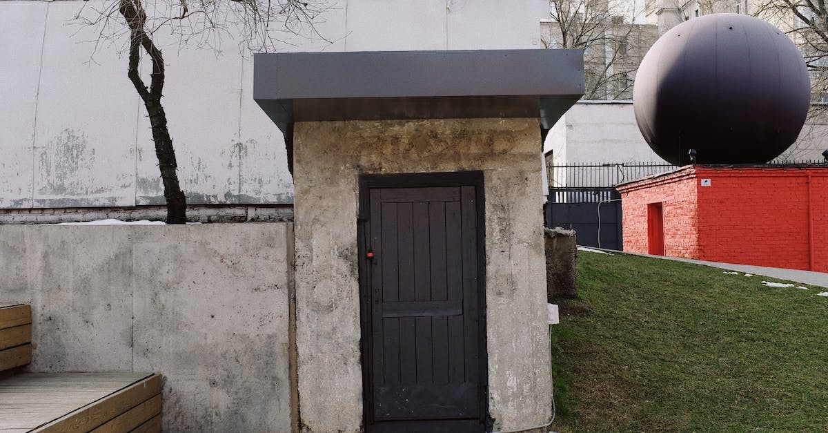 Second District Roof door is locked? - Facade of modern building with concrete walls and wooden black door located near red construction with big black ball on roof