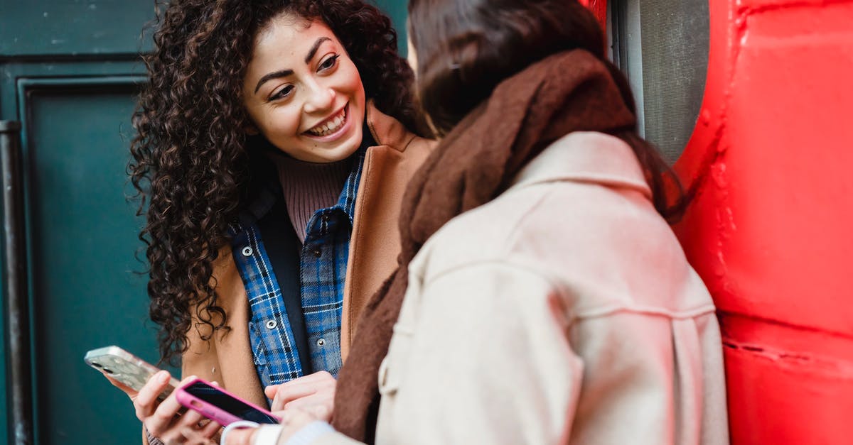 See Other Players Message Ratings - Smiling young multiracial ladies browsing smartphones and communicating on street See Other Players Message Ratings - Smiling young multiracial ladies browsing smartphones and communicating on street