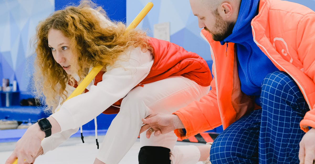 Select player not in a specific position - Man trainer fixing leg position of woman player in curling Select player not in a specific position - Man trainer fixing leg position of woman player in curling