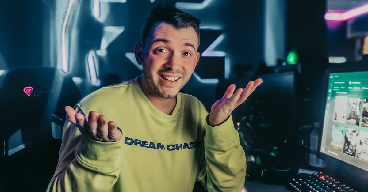 Select player not in a specific position - Bewildered man shrugging shoulders and looking at camera while sitting at table and choosing game to play on computer Select player not in a specific position - Bewildered man shrugging shoulders and looking at camera while sitting at table and choosing game to play on computer
