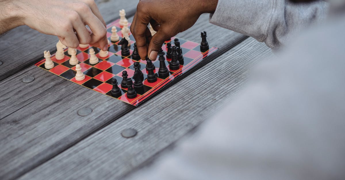 Select player that does not have a specific score set - Unrecognizable multiracial men playing chess at lumber table Select player that does not have a specific score set - Unrecognizable multiracial men playing chess at lumber table