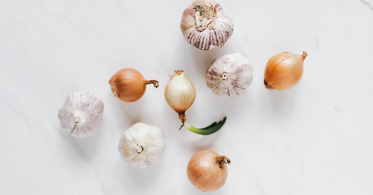 Set Bonus VS iLevel & Raw Stats [closed] - Top view composition of raw unpeeled ripe yellow onions and fresh whole aromatic garlic bulbs placed on white marble background