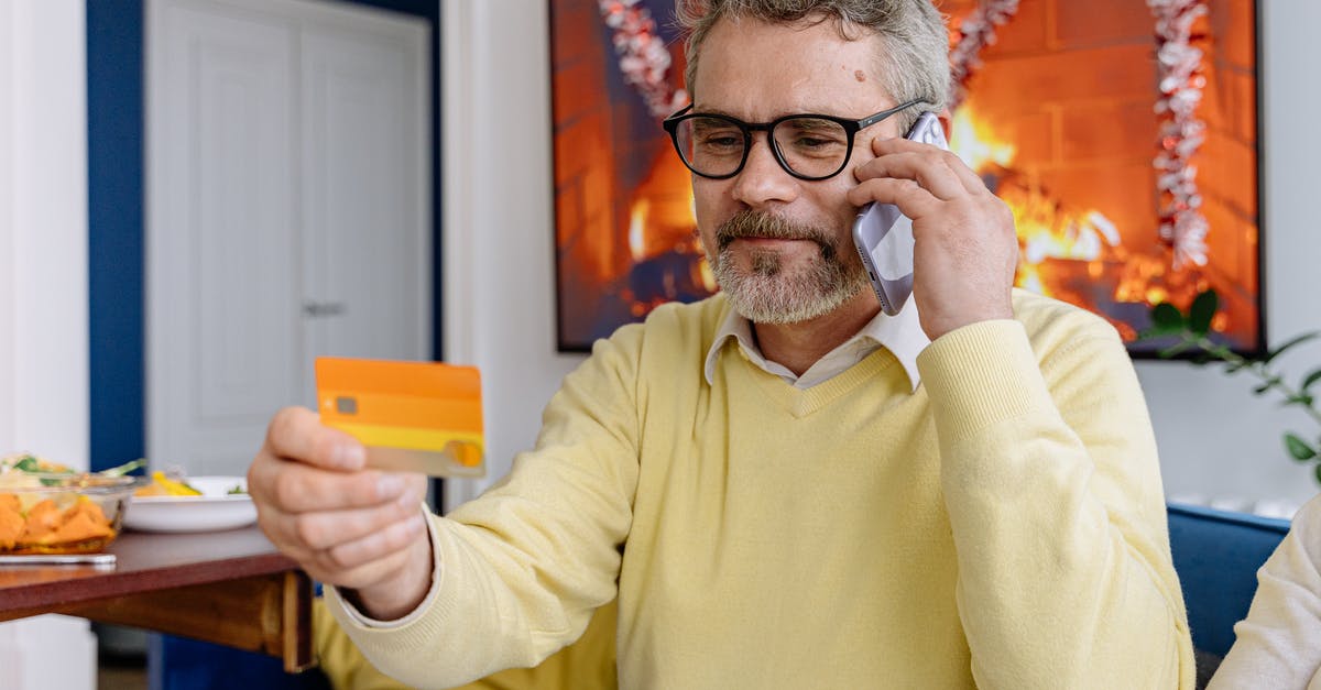 Sett's Calling Card - An Elderly Man Looking at a Card Holding a Cellphone to His Ear